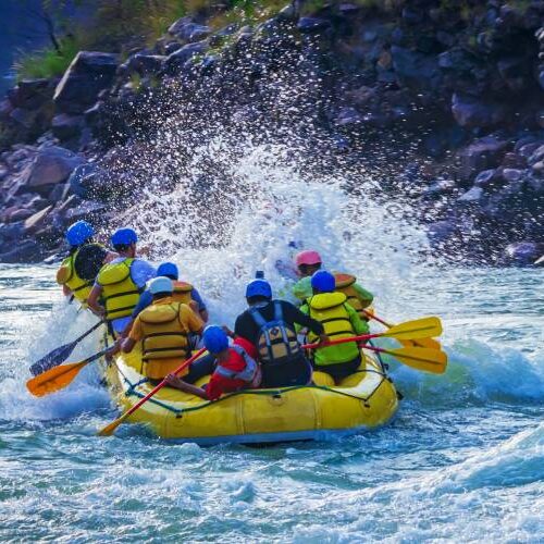 A diverse group of individuals navigating a river on inflatable rafts, surrounded by lush greenery and clear blue skies