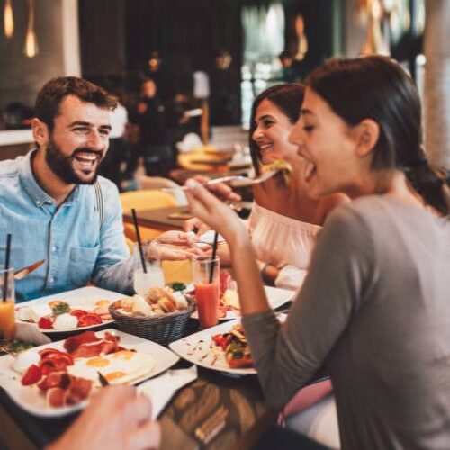 Friends gathered around a table in a restaurant, savoring delicious food and enjoying each other's company